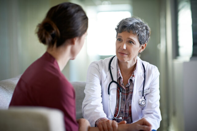 Female medical professional consulting with a patient in a clinic. She can focus on providing patient care rather than worry about her retirement savings since Fisher\SMB is helping her save money.