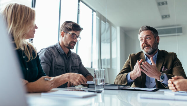 Professional retirement plan consultant reviewing documents with government representatives in a modern office setting, symbolizing trusted advisory services for public sector retirement plans.
