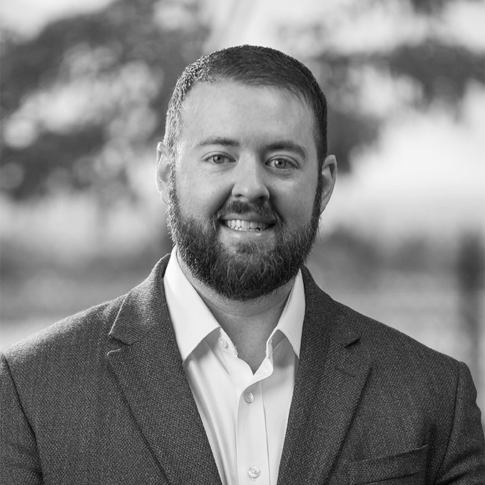 Black and white image of man with a beard in blazer smiling at the camera. This is Jim Davis' bio.