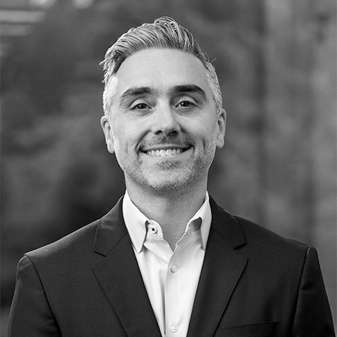 Black and White photo of white middle aged man wearing a blazer. This is Kyle Clark's bio.