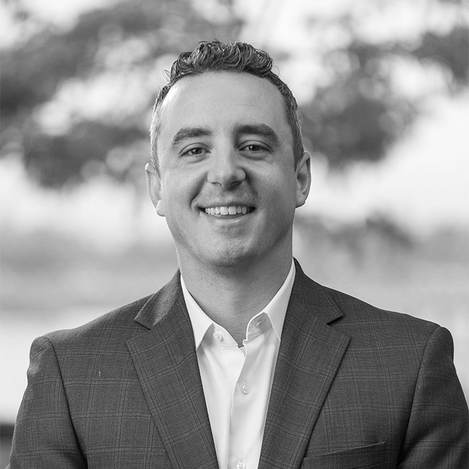 Black and white photo of a middle aged man smiling in a blazer. This is Jeff Sego's bio.
