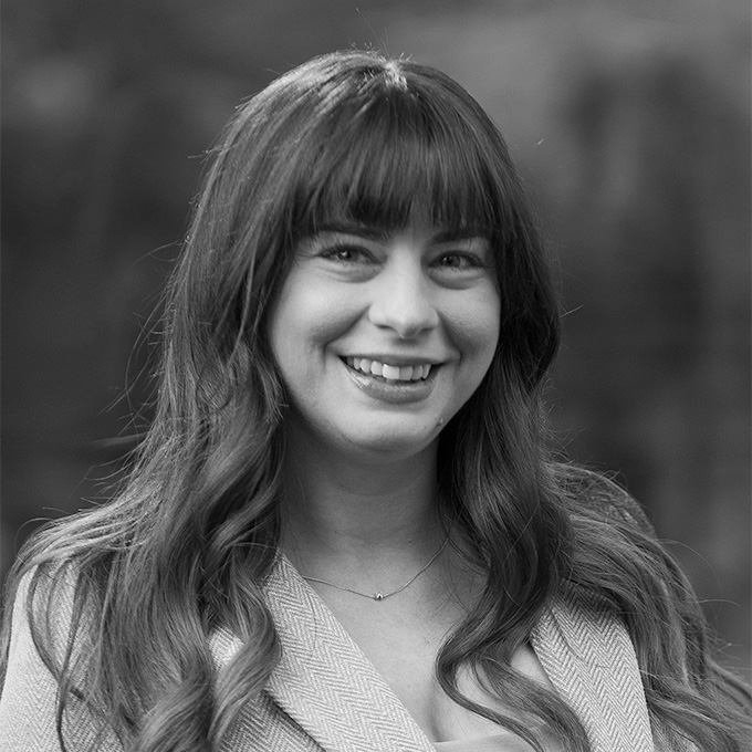 Black and white image of a woman with bangs smiling. This is Megan Reynolds bio