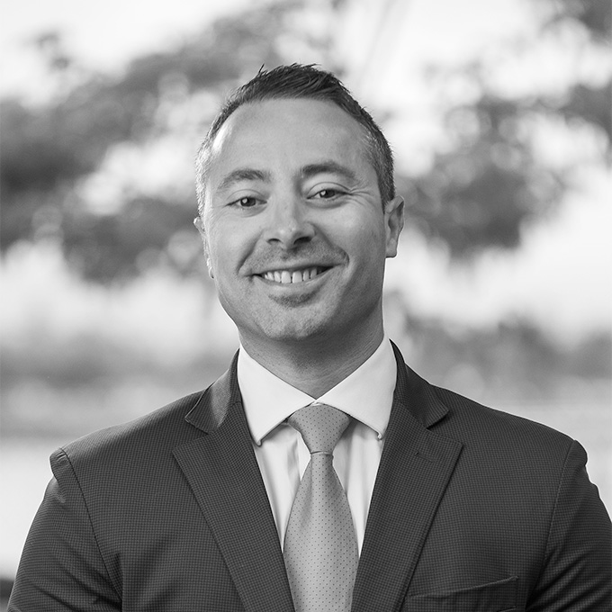 Black and white photo of a man smiling in a suit and tie. This is Pete Calvo's bio.