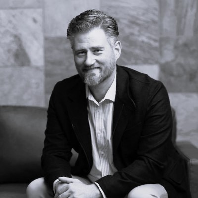 Black and white photo of male smiling in a blazer. This is Jesse Henley's bio